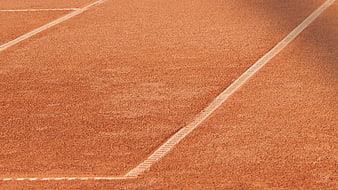 Close-up of red clay tennis court surface with white lines