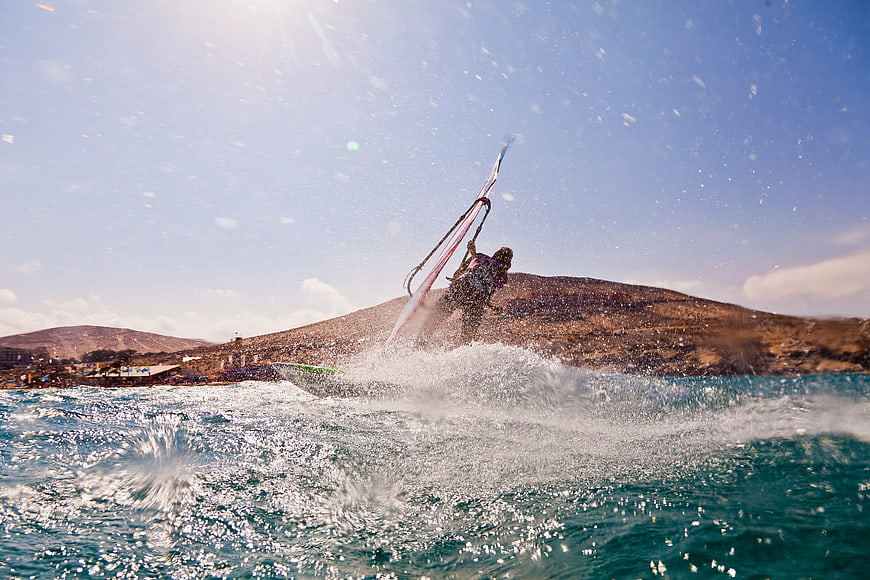 Windsurfer carving through waves on sunny day