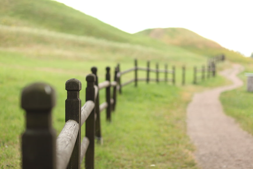 Rustic wooden fence along a winding path in green rolling hills
