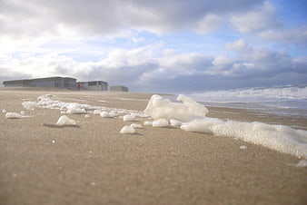 Low angle view of sea foam on sandy beach with ocean waves