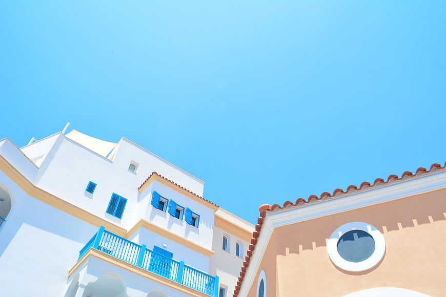 Mediterranean Architecture With Blue Shutters And Terracotta Roof Against Clear Sky