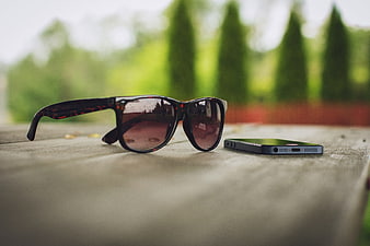 Sunglasses and Smartphone on Wooden Table Outdoors