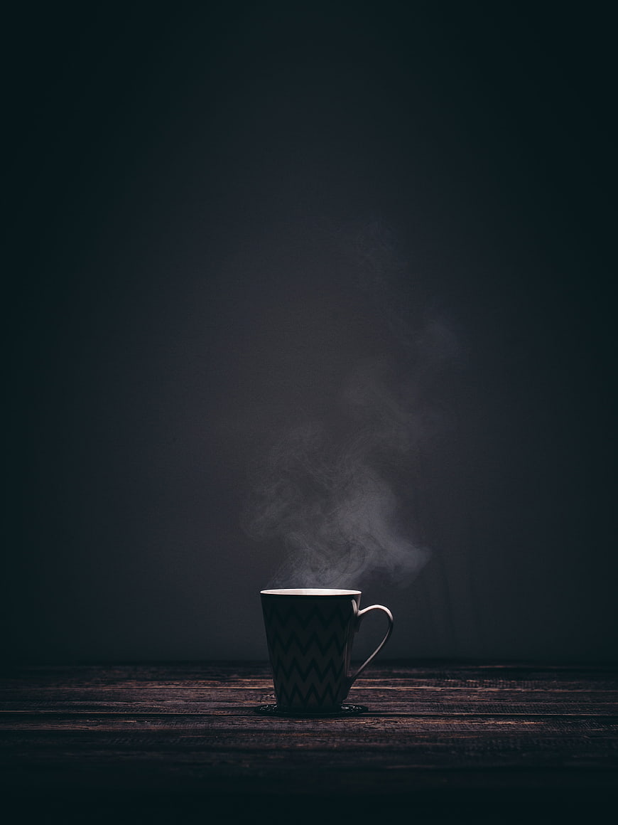 Steaming Coffee Mug on Dark Wooden Table with Dramatic Smoke
