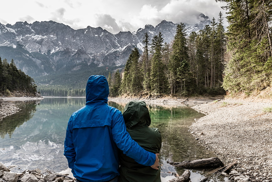 Couple in Raincoats Looking at Mountain Lake