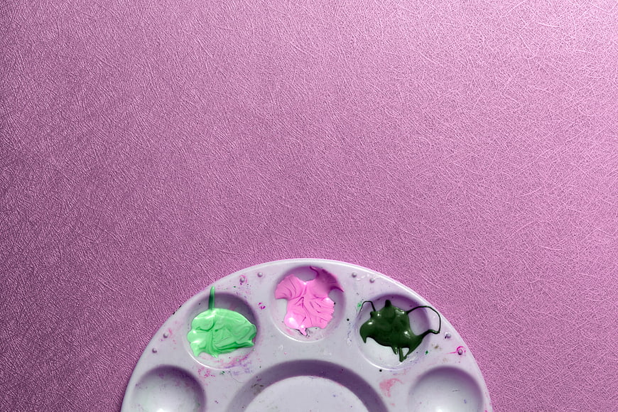 Paint Palette with Pink and Green Paint on Purple Background
