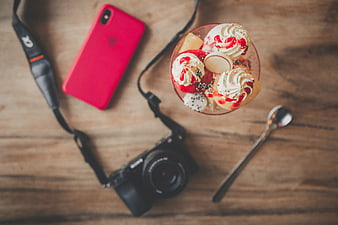 Flat lay of dessert, camera, and smartphone on wooden table