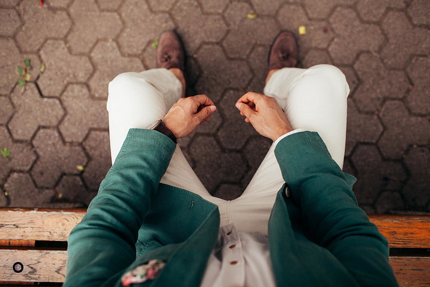 First-person view of man in green jacket sitting on bench