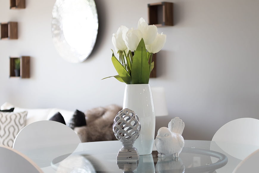 White tulips in vase on glass dining table interior