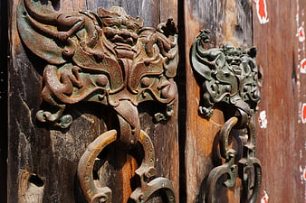 Ancient Bronze Door Knocker on Weathered Wooden Temple Door