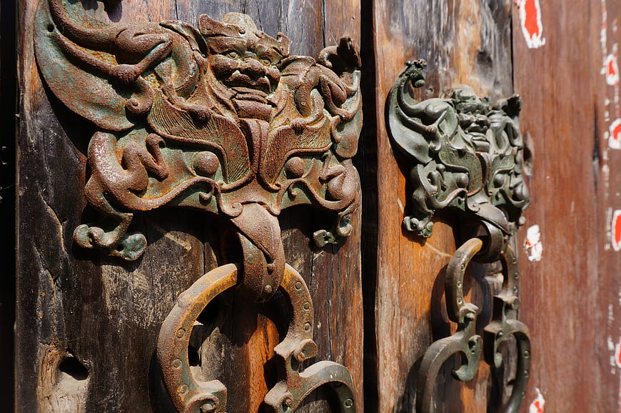 Ancient Bronze Door Knocker on Weathered Wooden Temple Door