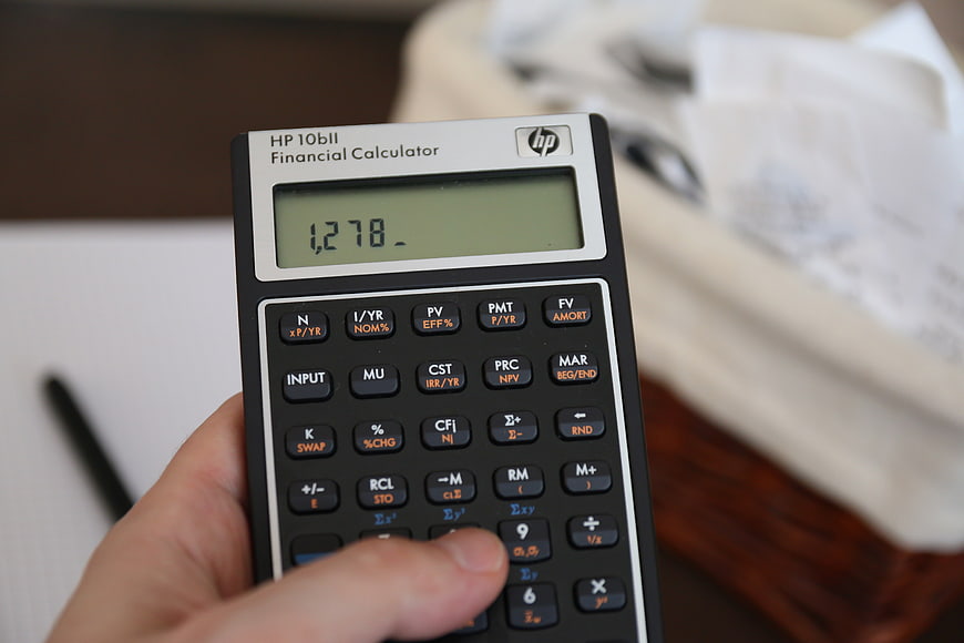 Hand holding HP 10bII financial calculator displaying numbers