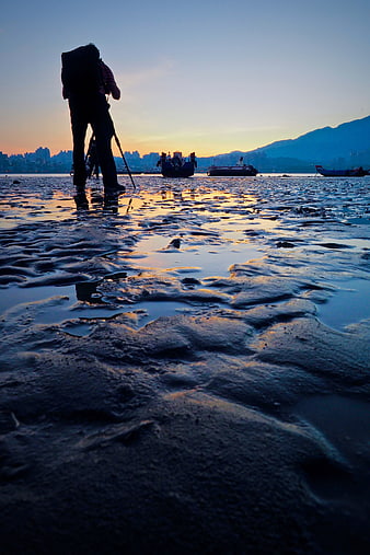 Silhouette of Hiker on Muddy Beach at Sunset