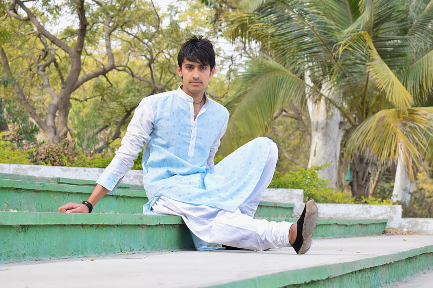 Young man in traditional Indian kurta sitting on steps