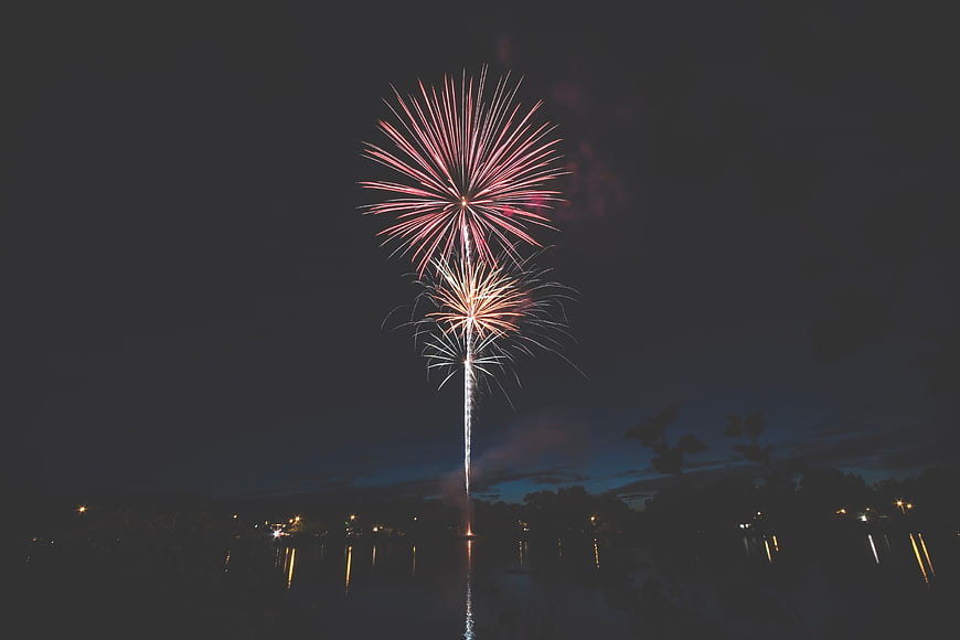 Pink and Gold Fireworks Exploding Over Night Sky