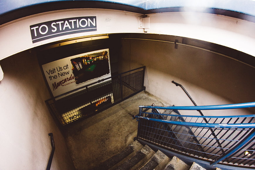 Fisheye view of subway stairs with blue railing and advertisement