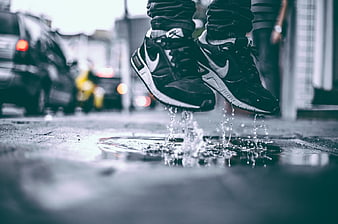 Man Jumping in Puddle Wearing Black Nike Sneakers