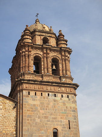 Historic stone church bell tower against blue sky
