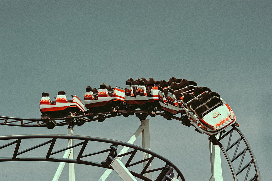 Empty Roller Coaster Cars on Track Against Blue Sky
