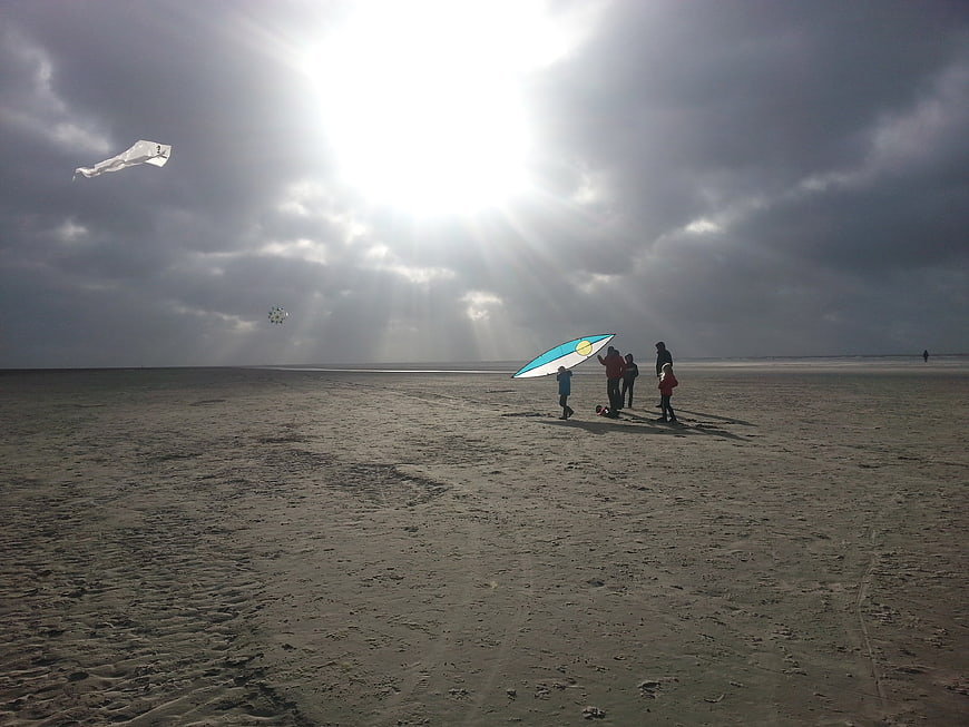 Family Flying Kites on Sandy Beach Under Dramatic Sunbeams