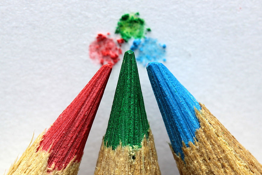 Close-up of red, green, and blue colored pencil tips on white paper