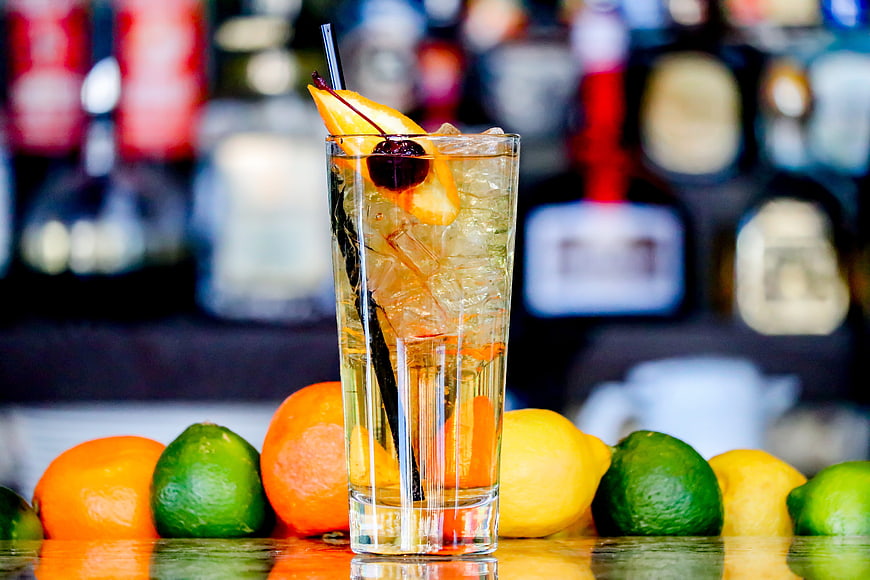 Refreshing Citrus Cocktail Garnished With Peach And Cherry On Bar Counter