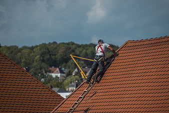 Roofer climbing ladder on red tiled roof