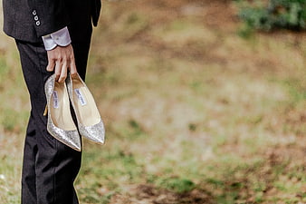 Groom holding silver wedding shoes outdoors