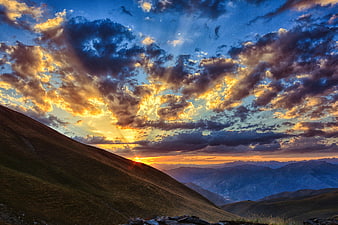 Dramatic Sunset Over Mountain Ranges With Golden Clouds