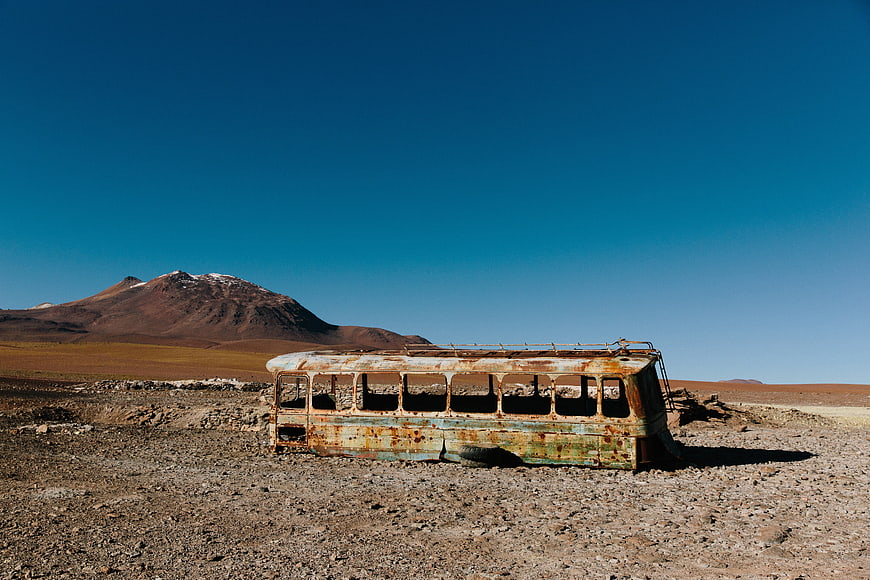 Abandoned Rusty Bus in Desert Landscape with Mountain