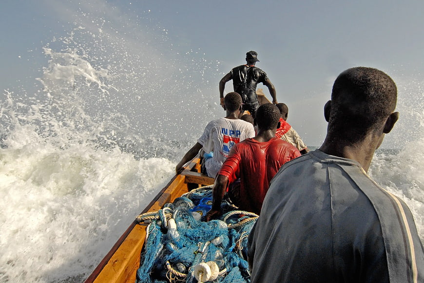 Fishermen on wooden boat with blue nets in ocean