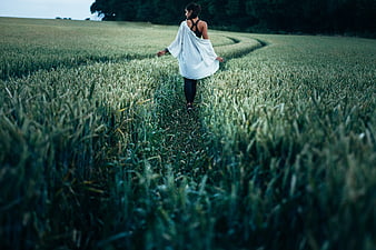 Woman walking through a green wheat field in the countryside