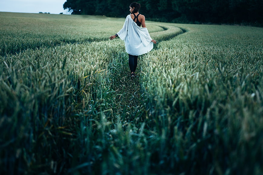 Woman walking through a green wheat field in the countryside