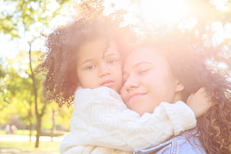 Mother and daughter hugging in sunlit park
