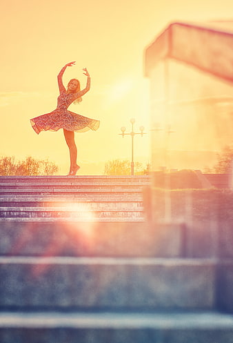 Ballerina dancing on steps at golden hour sunset