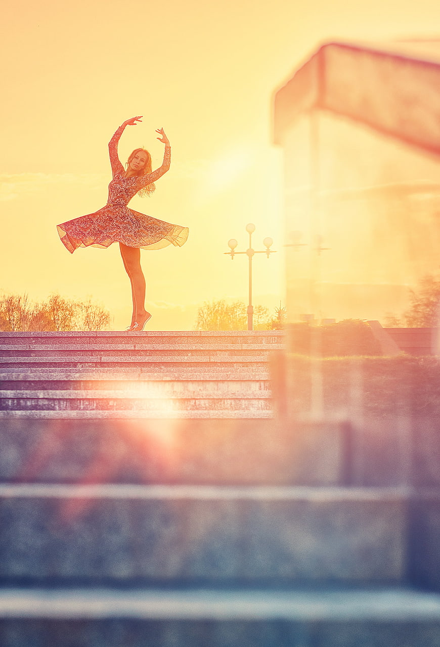 Ballerina dancing on steps at golden hour sunset