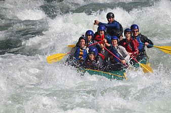 Group of friends white water rafting in rapids