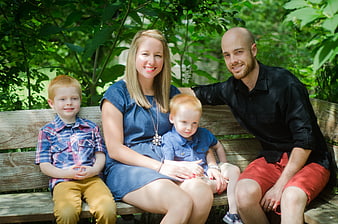 Happy Family Portrait Sitting On Park Bench