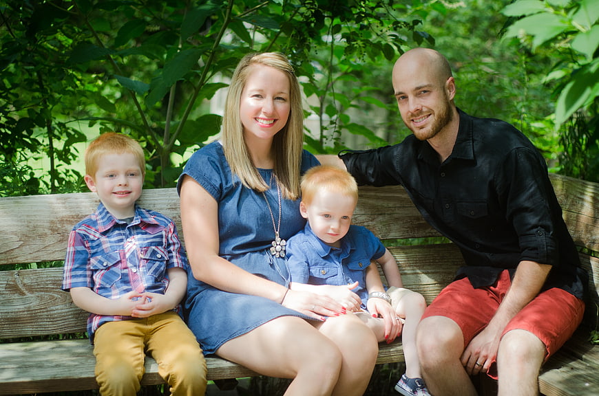 Happy Family Portrait Sitting On Park Bench