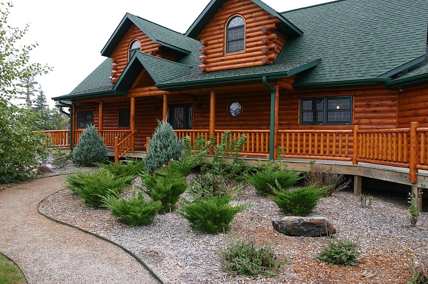 Exterior of a rustic log cabin home with landscaped garden and gravel path