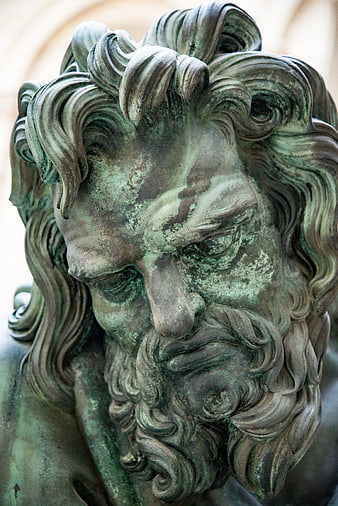 Close-up of weathered bronze statue head with green patina