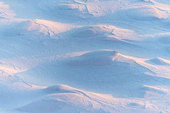 Aerial view of rolling snow dunes with golden hour light