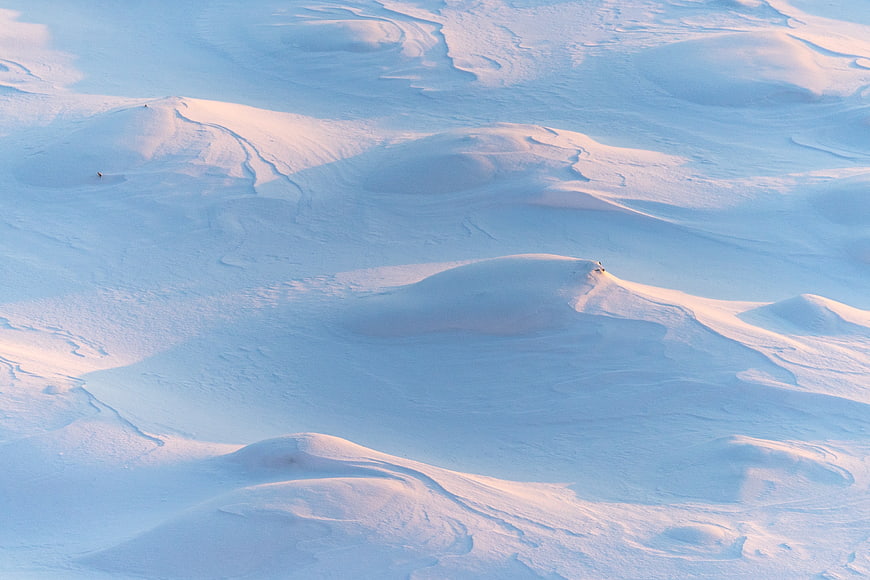 Aerial view of rolling snow dunes with golden hour light