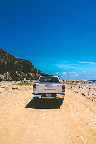 White pickup truck on sandy road near Bonaire beach