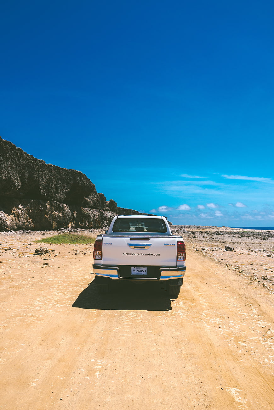 White pickup truck on sandy road near Bonaire beach