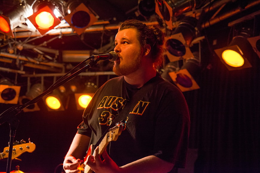 Male musician singing and playing guitar on stage