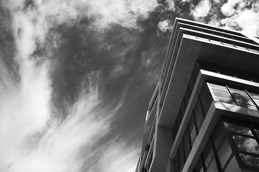 Black and white low angle view of modern building against dramatic clouds