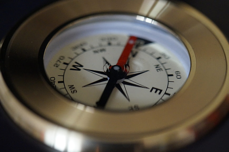 Close-up of a brass compass with a red and black needle