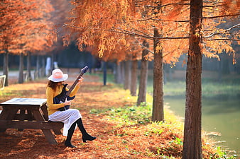 Woman Playing Electric Guitar On Picnic Table In Autumn Park