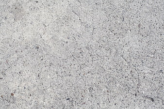 Close-up texture of weathered gray concrete wall with small cracks and pebbles