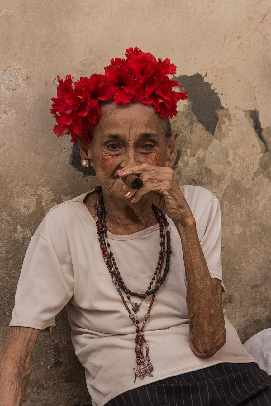 Portrait of elderly Cuban woman with red carnations and cigar